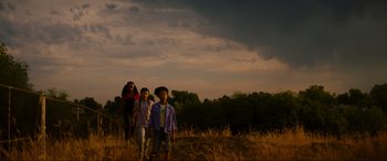 Movie still from “Summering” (2022), directed by James Ponsoldt – A group of people standing on top of a dry grass field; Extreme Wide shot, Low angle