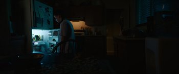 Movie still from “Summering” (2022), directed by James Ponsoldt – A man standing at a table in a dark kitchen; Medium shot, Low angle