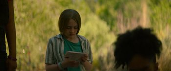 Movie still from “Summering” (2022), directed by James Ponsoldt – A girl is reading a book in a park; Close Up shot, Over the shoulder angle