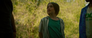 Movie still from “Summering” (2022), directed by James Ponsoldt – A girl in a green shirt looking up at a tree; Medium shot, Over the shoulder angle