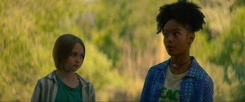 Movie still from “Summering” (2022), directed by James Ponsoldt – Two young people standing next to each other in front of trees; Medium shot, Low angle