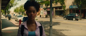 Movie still from “Summering” (2022), directed by James Ponsoldt – A woman standing next to a pole on the sidewalk; Medium shot, Low angle