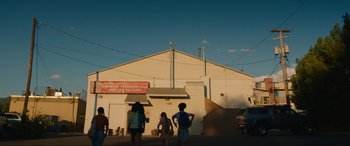 Movie still from “Summering” (2022), directed by James Ponsoldt – A group of people standing in front of a white building; Extreme Wide shot, Low angle