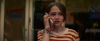 Movie still from “Summering” (2022), directed by James Ponsoldt – A young girl talking on a cell phone; Close Up shot, High angle