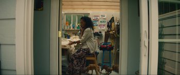 Movie still from “Summering” (2022), directed by James Ponsoldt – A woman sitting on a chair in a room; Wide shot, Low angle