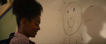 Movie still from “Summering” (2022), directed by James Ponsoldt – A young girl is smiling in front of a drawing of a smiling face; Close Up shot, Over the shoulder angle