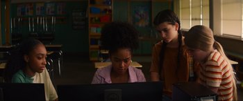 Movie still from “Summering” (2022), directed by James Ponsoldt – Two young girls looking at a computer screen in a classroom; Medium shot, Over the shoulder angle