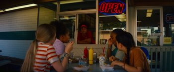 Movie still from “Summering” (2022), directed by James Ponsoldt – A group of people sitting at a table with food; Medium shot, Low angle
