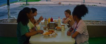 Movie still from “Summering” (2022), directed by James Ponsoldt – A group of people sitting at a table with drinks and food; Medium shot, High angle