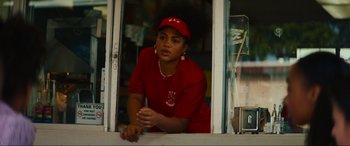 Movie still from “Summering” (2022), directed by James Ponsoldt – A woman in a red shirt leaning against a window; Medium shot, Over the shoulder angle
