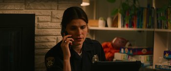 Movie still from “Summering” (2022), directed by James Ponsoldt – A police officer talking on a cell phone while sitting at a table; Close Up shot, Over the shoulder angle