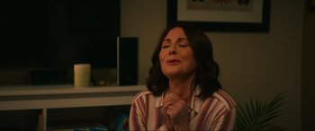 Movie still from “Summering” (2022), directed by James Ponsoldt – A woman with her hands clasped in front of her face; Medium shot, Over the shoulder angle