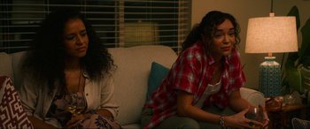Movie still from “Summering” (2022), directed by James Ponsoldt – Two women sitting on a couch in a living room; Medium shot, Over the shoulder angle
