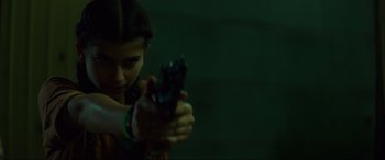Movie still from “Summering” (2022), directed by James Ponsoldt – A young girl holding a gun in a dark room; Close Up shot, Over the shoulder angle