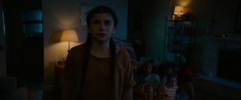 Movie still from “Summering” (2022), directed by James Ponsoldt – A woman with braids standing in a room with a group of children; Medium shot, Low angle