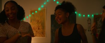 Movie still from “Summering” (2022), directed by James Ponsoldt – A young woman smiles brightly at the camera; Medium shot, Over the shoulder angle