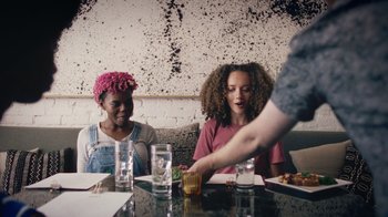 Movie still from “Summertime” (2020), directed by Carlos López Estrada – Two women sitting at a table with plates of food; Medium shot, Over the shoulder angle
