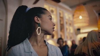 Movie still from “Summertime” (2020), directed by Carlos López Estrada – A woman wearing a white shirt and green earrings; Close Up shot, Over the shoulder angle