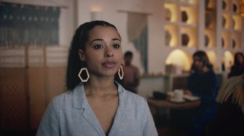 Movie still from “Summertime” (2020), directed by Carlos López Estrada – A woman with long hair wearing a white shirt and wooden earrings; Close Up shot, Over the shoulder angle