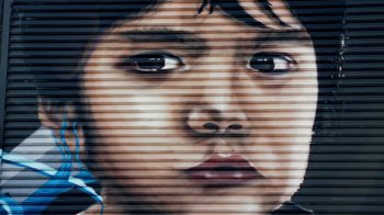 Movie still from “Summertime” (2020), directed by Carlos López Estrada – A person's face painted on the side of a building; Extreme Close Up shot, Low angle