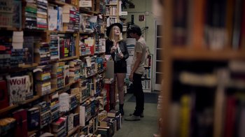 Movie still from “Summertime” (2020), directed by Carlos López Estrada – A woman and a man standing in front of a wall of books; Wide shot, Over the shoulder angle