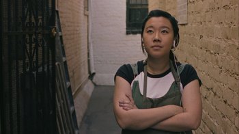Movie still from “Summertime” (2020), directed by Carlos López Estrada – A woman standing in a doorway with her arms crossed; Close Up shot, High angle