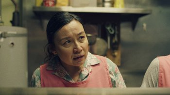 Movie still from “Summertime” (2020), directed by Carlos López Estrada – A woman in a pink apron is sitting in a kitchen; Close Up shot, Over the shoulder angle