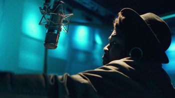 Movie still from “Summertime” (2020), directed by Carlos López Estrada – A man with a microphone in front of a microphone stand; Close Up shot, Low angle