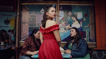 Movie still from “Summertime” (2020), directed by Carlos López Estrada – A woman in a red dress standing in front of two other women; Medium shot, Low angle