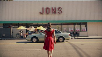 Movie still from “Summertime” (2020), directed by Carlos López Estrada – A woman in a red dress standing in front of a store; Extreme Wide shot, Low angle