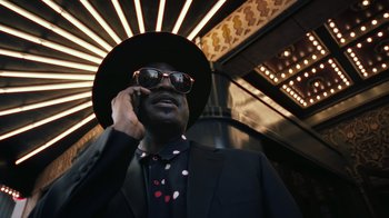 Movie still from “Summertime” (2020), directed by Carlos López Estrada – A man wearing a hat and sunglasses talking on a cell phone; Medium shot, Low angle