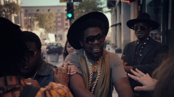 Movie still from “Summertime” (2020), directed by Carlos López Estrada – A man with a hat and a beard on the street; Medium shot, Over the shoulder angle
