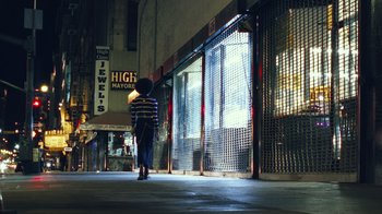 Movie still from “Summertime” (2020), directed by Carlos López Estrada – A person walking down a street at night; Extreme Wide shot, Low angle