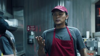 Movie still from “Summertime” (2020), directed by Carlos López Estrada – A man wearing an apron and a hat standing next to a wall; Medium shot, Over the shoulder angle