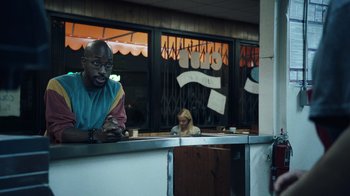 Movie still from “Summertime” (2020), directed by Carlos López Estrada – A man sitting at a counter in front of a woman; Medium shot, Over the shoulder angle