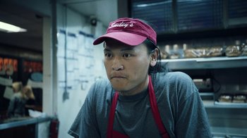 Movie still from “Summertime” (2020), directed by Carlos López Estrada – A man wearing a red hat and a gray shirt; Close Up shot, Low angle
