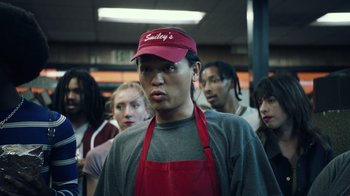 Movie still from “Summertime” (2020), directed by Carlos López Estrada – A group of people standing in a line wearing aprons and hats; Medium shot, Low angle