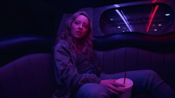 Movie still from “Summertime” (2020), directed by Carlos López Estrada – A woman sitting in a limo holding a drink; Medium shot, Low angle