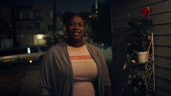 Movie still from “Summertime” (2020), directed by Carlos López Estrada – A woman standing in front of a building at night; Medium shot, Over the shoulder angle