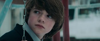 Movie still from “Super 8” (2011), directed by J.J. Abrams – A young boy with long brown hair wearing a suit; Close Up shot, Low angle