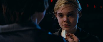 Movie still from “Super 8” (2011), directed by J.J. Abrams – A young woman looking into a mirror while wearing a tie; Close Up shot, Over the shoulder angle