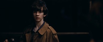 Movie still from “Super 8” (2011), directed by J.J. Abrams – A young man in a brown jacket is looking at the camera; Close Up shot, Over the shoulder angle