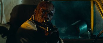 Movie still from “Super 8” (2011), directed by J.J. Abrams – A man with a zombie face holding a gun; Close Up shot, Low angle
