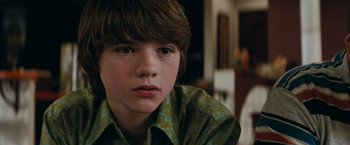 Movie still from “Super 8” (2011), directed by J.J. Abrams – A young boy with long brown hair wearing a green shirt; Close Up shot, Over the shoulder angle