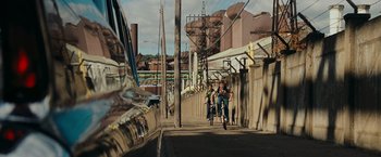 Movie still from “Super 8” (2011), directed by J.J. Abrams – Two people riding bikes down a street next to power lines; Extreme Wide shot, High angle