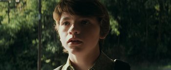 Movie still from “Super 8” (2011), directed by J.J. Abrams – A young boy with a brown shirt is looking at the camera; Close Up shot, Low angle
