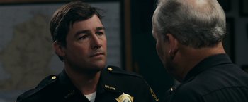 Movie still from “Super 8” (2011), directed by J.J. Abrams – Two police officers talking to each other in a room; Close Up shot, Over the shoulder angle