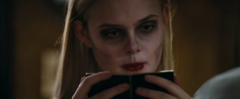 Movie still from “Super 8” (2011), directed by J.J. Abrams – A woman with makeup on her face is holding a book; Close Up shot, Over the shoulder angle