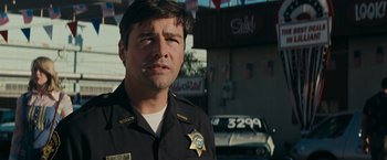 Movie still from “Super 8” (2011), directed by J.J. Abrams – A man in a police uniform standing in front of a building; Close Up shot, Low angle