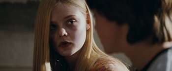 Movie still from “Super 8” (2011), directed by J.J. Abrams – A young woman with long blonde hair looking at the camera; Close Up shot, Over the shoulder angle